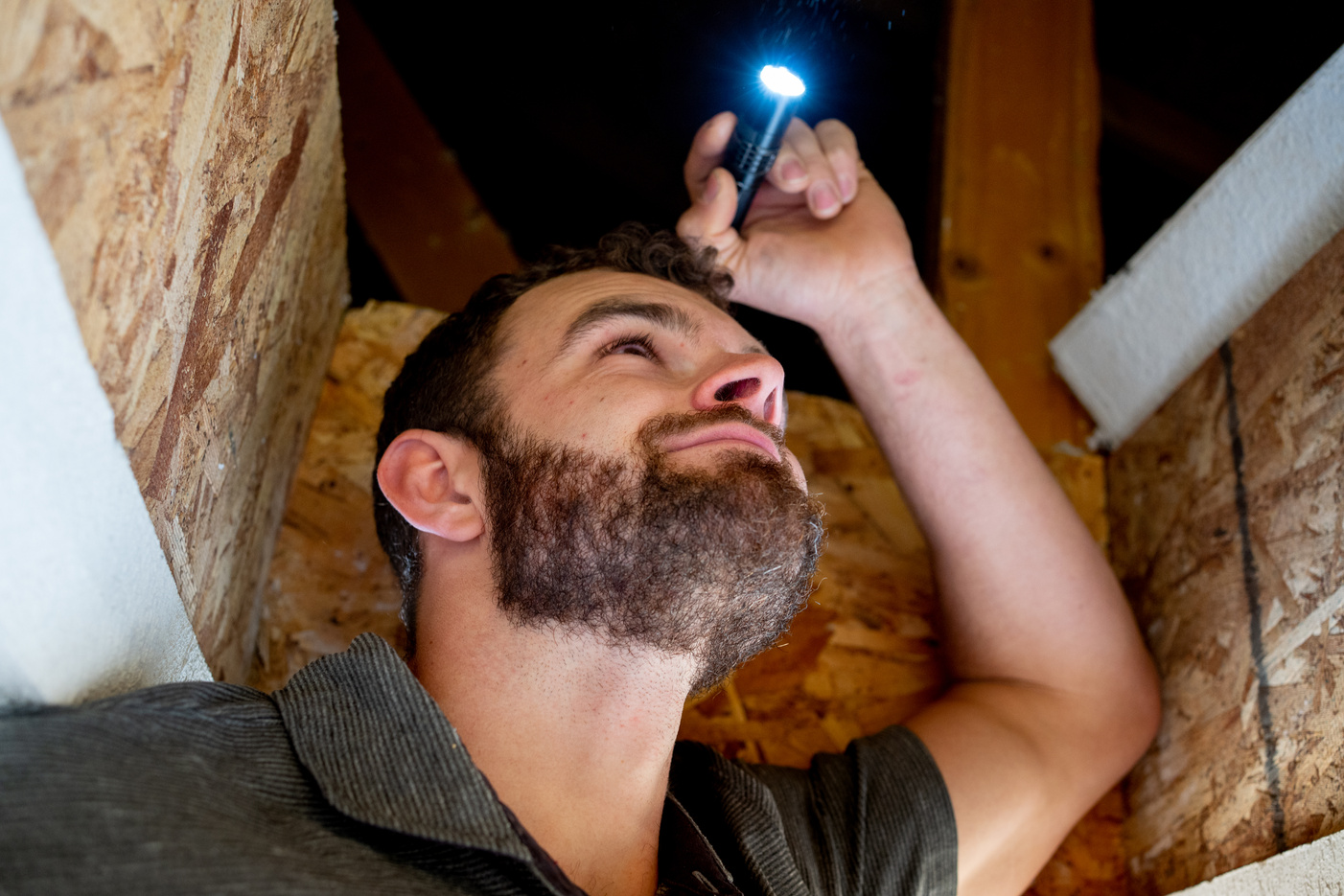 Young Male Home Inspector Looking Into an Attic of a Single Family Home